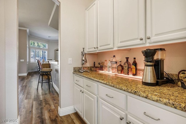 bar featuring ornamental molding, dark wood-type flooring, a dry bar, and baseboards