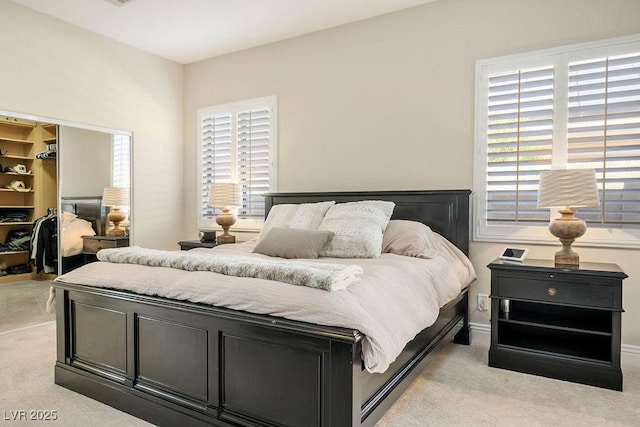 bedroom with light carpet, multiple windows, a walk in closet, and a closet