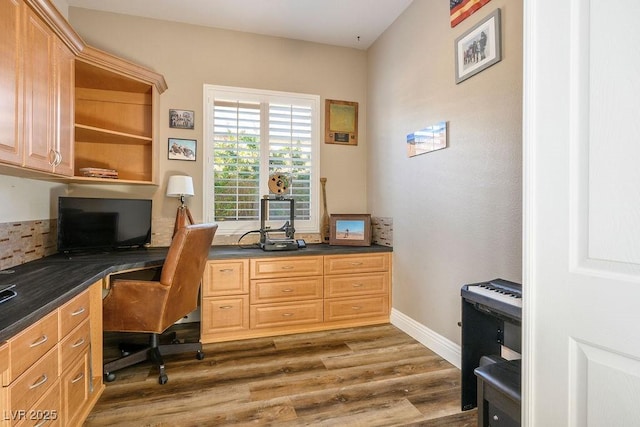 office with dark wood-type flooring, built in desk, and baseboards