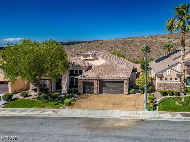 view of front facade with stucco siding, stone siding, concrete driveway, a garage, and a tiled roof