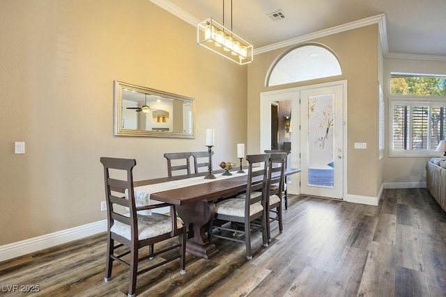 dining room with dark wood-type flooring, visible vents, crown molding, and baseboards