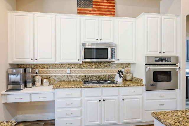 kitchen with light stone countertops, appliances with stainless steel finishes, white cabinets, and backsplash