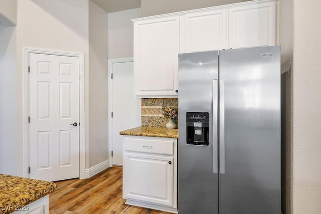 kitchen with tasteful backsplash, dark stone counters, white cabinets, and stainless steel fridge