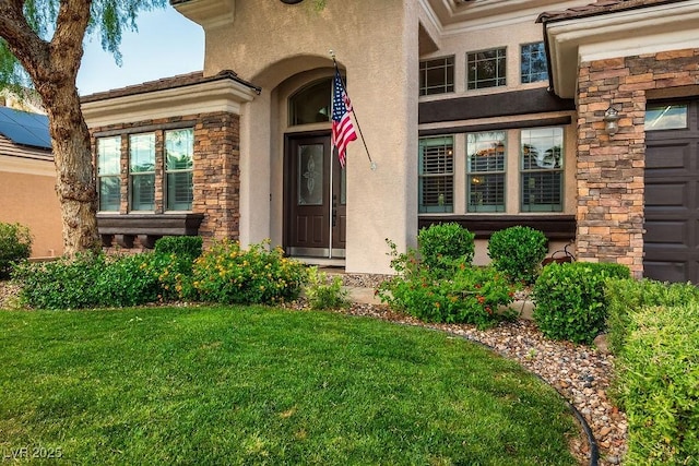 entrance to property with stone siding, a yard, and stucco siding