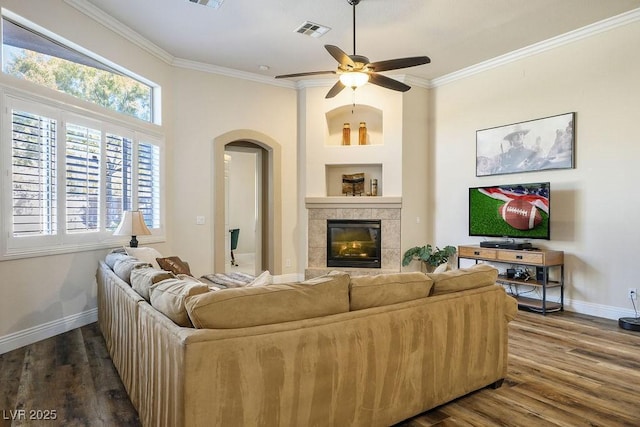 living area with ornamental molding, arched walkways, visible vents, and a fireplace