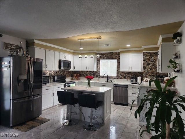 kitchen featuring sink, a kitchen island, pendant lighting, stainless steel appliances, and white cabinets