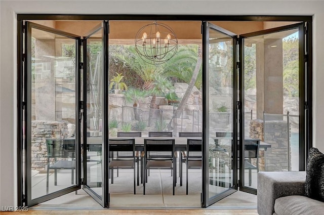 doorway to outside featuring a wall of windows, plenty of natural light, and a notable chandelier