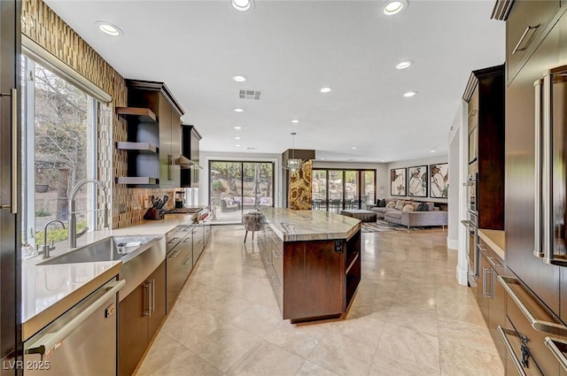 kitchen featuring sink, dark brown cabinets, stainless steel appliances, a kitchen island, and decorative light fixtures