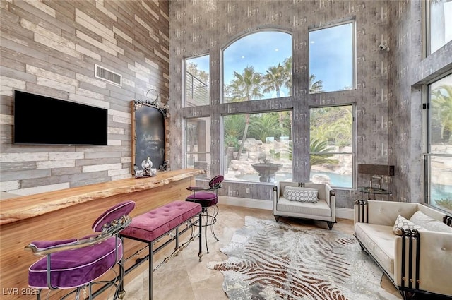 living room featuring indoor bar, plenty of natural light, and a high ceiling