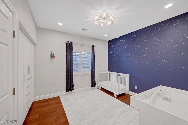 unfurnished bedroom with wood-type flooring and a nursery area