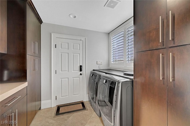 laundry room featuring washer and dryer, light tile patterned floors, and cabinets