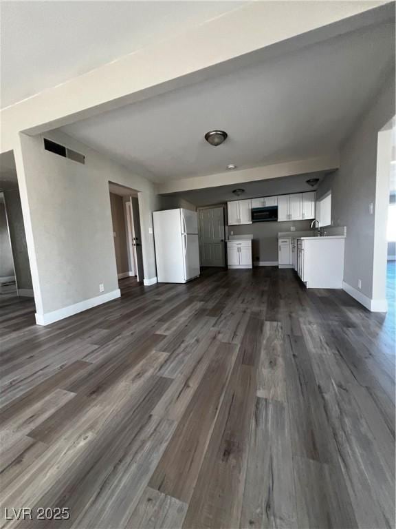 unfurnished living room featuring dark wood-type flooring and sink