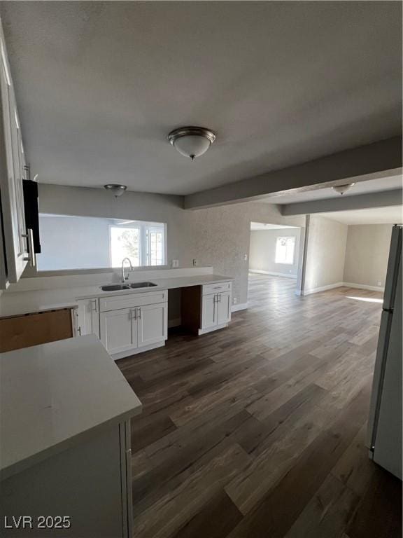 kitchen featuring sink, dark wood-type flooring, stainless steel refrigerator, and white cabinets