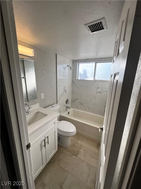 full bathroom featuring vanity, toilet, a textured ceiling, and tiled shower / bath