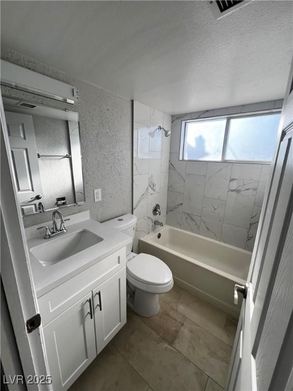 full bathroom featuring tiled shower / bath combo, vanity, a textured ceiling, and toilet