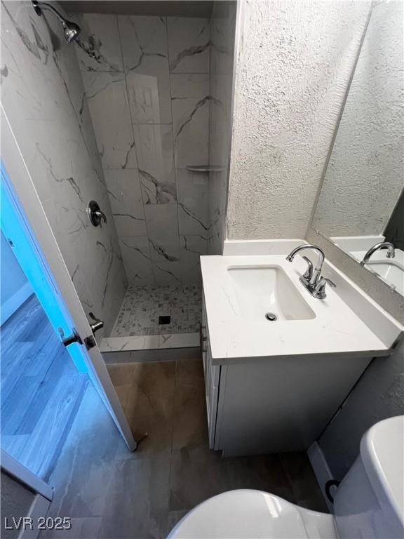 bathroom featuring tiled shower, vanity, and toilet