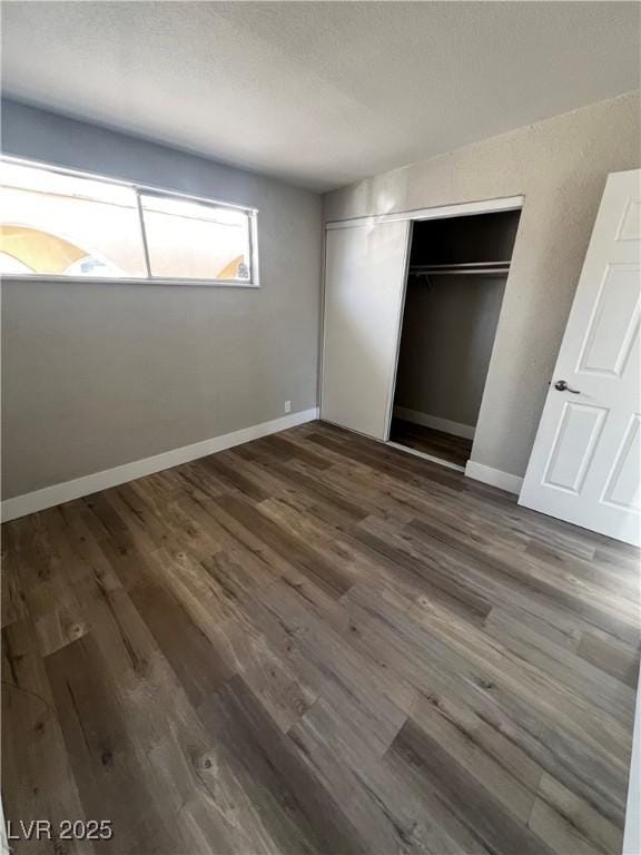 unfurnished bedroom with dark wood-type flooring and a closet