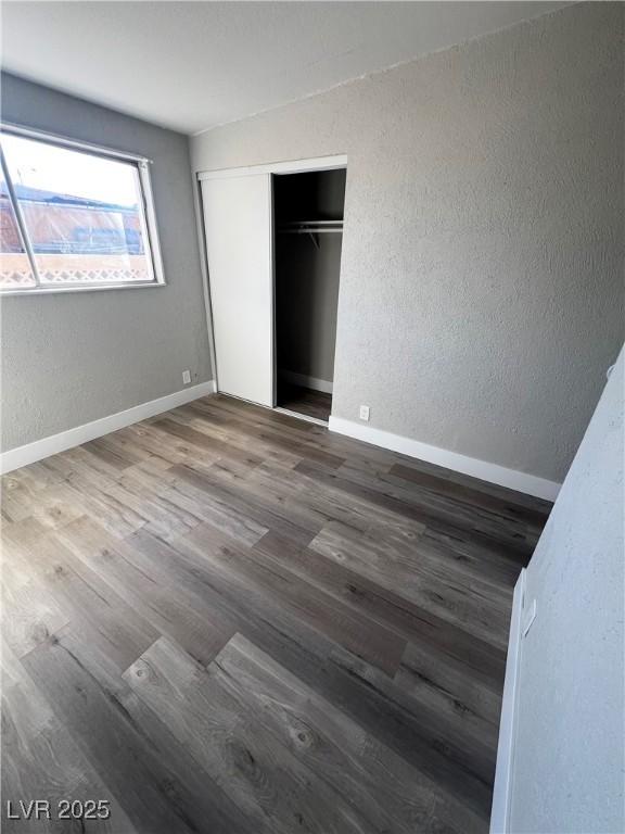 unfurnished bedroom featuring dark wood-type flooring and a closet