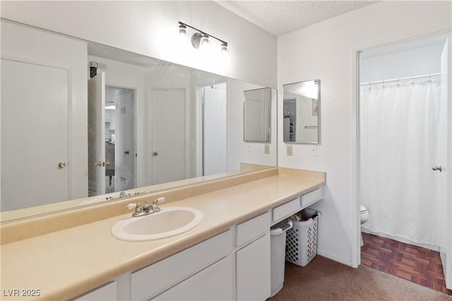 bathroom with parquet floors, vanity, toilet, and a textured ceiling