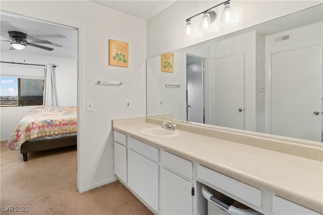 bathroom with ceiling fan, vanity, and a textured ceiling