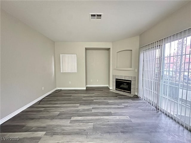 unfurnished living room with baseboards, a fireplace, visible vents, and wood finished floors