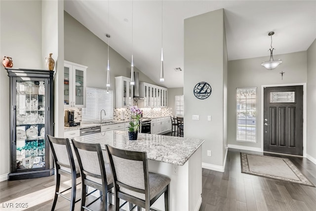 kitchen with white cabinetry, decorative light fixtures, a kitchen breakfast bar, a kitchen island, and backsplash