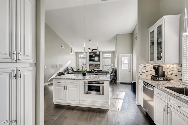 kitchen with white cabinetry, decorative backsplash, ceiling fan, light stone counters, and stainless steel appliances