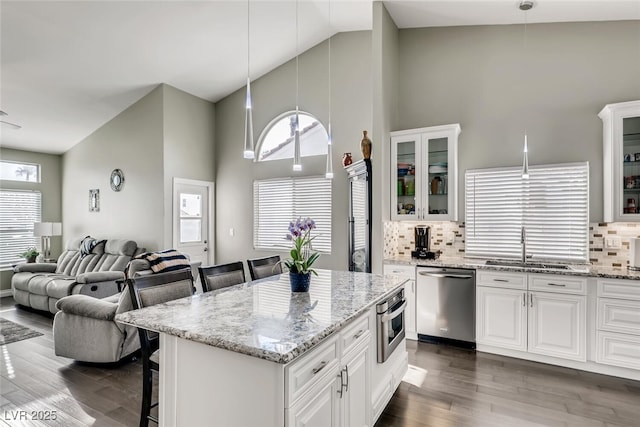 kitchen featuring stainless steel appliances, decorative light fixtures, a kitchen breakfast bar, and white cabinets