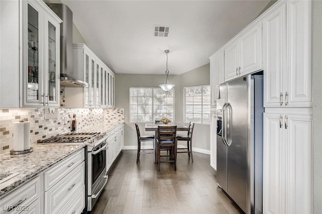 kitchen featuring pendant lighting, white cabinetry, decorative backsplash, stainless steel appliances, and light stone countertops