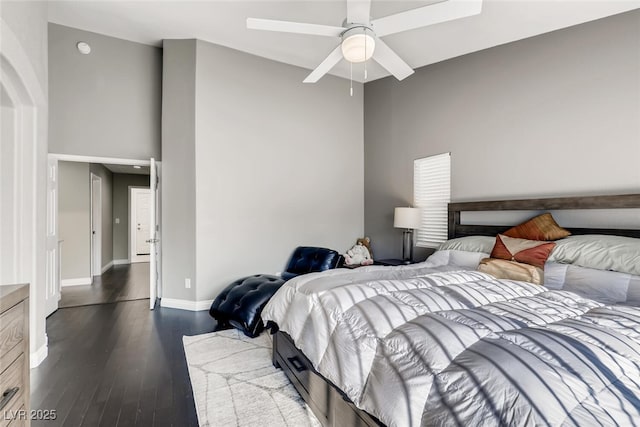 bedroom with dark hardwood / wood-style floors, ceiling fan, and a high ceiling