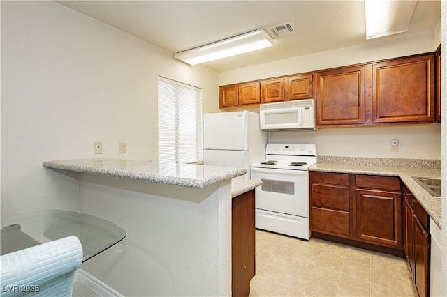 kitchen with light stone countertops, sink, white appliances, and kitchen peninsula