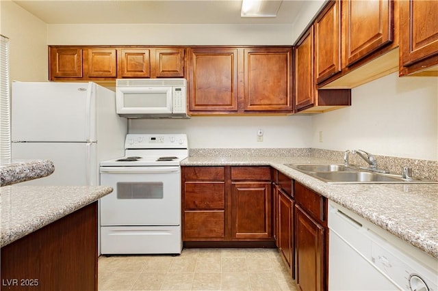 kitchen featuring white appliances, light stone countertops, and sink