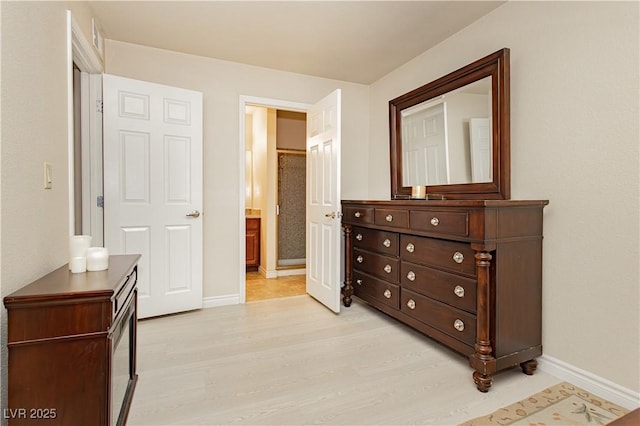 bedroom featuring connected bathroom and light wood-type flooring