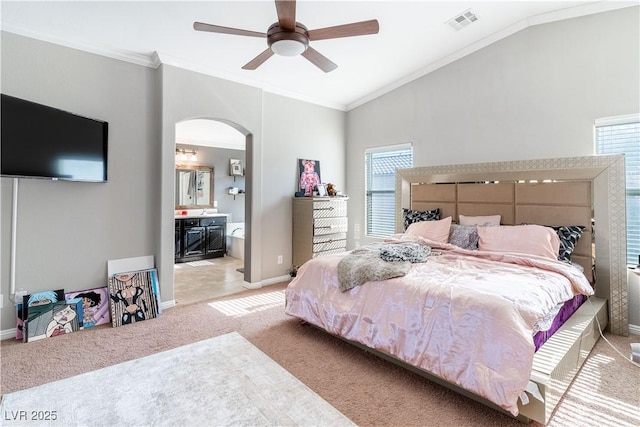 carpeted bedroom featuring lofted ceiling, crown molding, ensuite bath, and ceiling fan