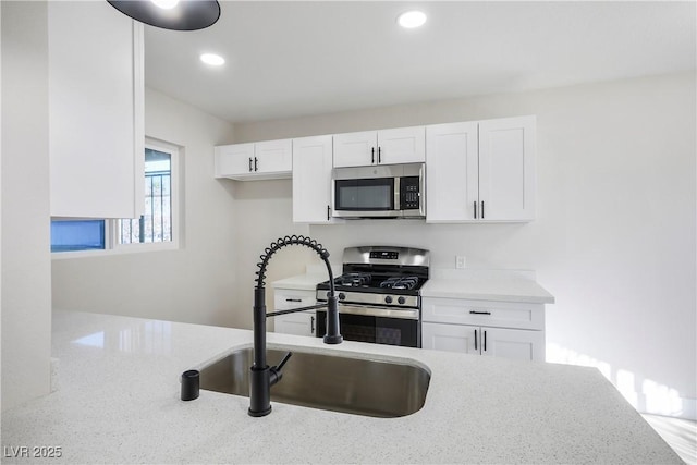 kitchen with white cabinetry, sink, stainless steel appliances, and light stone countertops