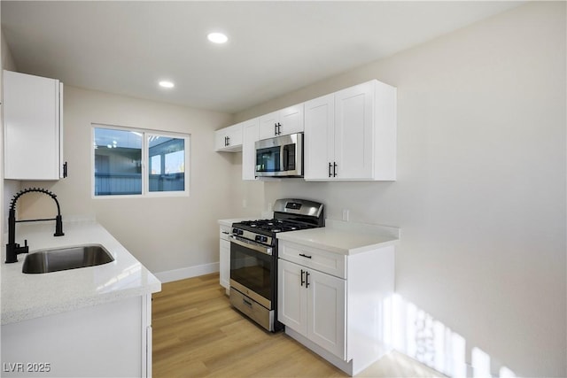 kitchen featuring light wood-type flooring, appliances with stainless steel finishes, sink, and white cabinets