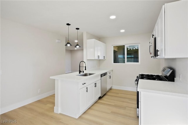 kitchen with appliances with stainless steel finishes, decorative light fixtures, white cabinetry, sink, and kitchen peninsula