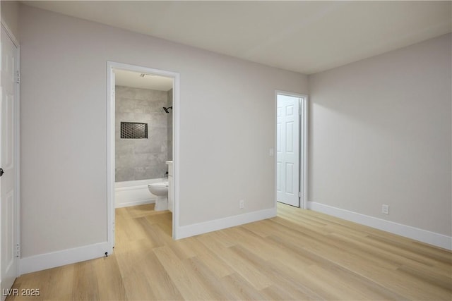 unfurnished bedroom featuring connected bathroom and light hardwood / wood-style flooring