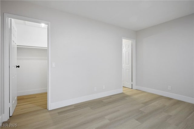 unfurnished bedroom featuring a walk in closet, light hardwood / wood-style floors, and a closet