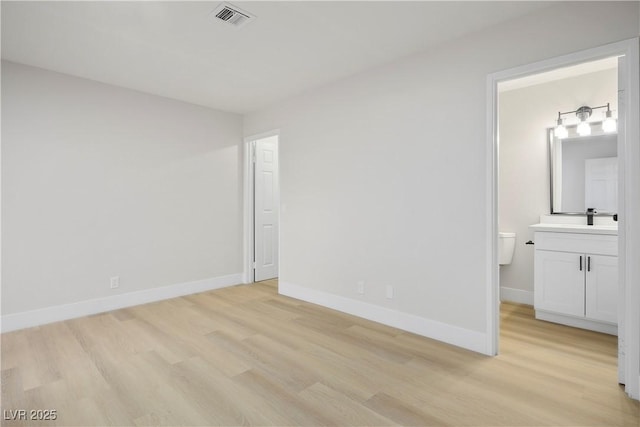 unfurnished bedroom with sink, ensuite bath, and light hardwood / wood-style flooring