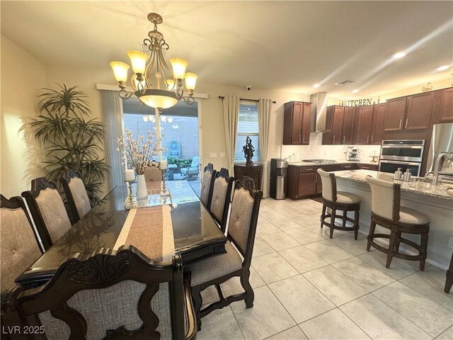 tiled dining area featuring an inviting chandelier and sink