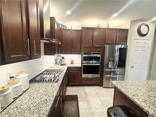 kitchen featuring light stone counters, stainless steel appliances, light tile patterned flooring, and backsplash