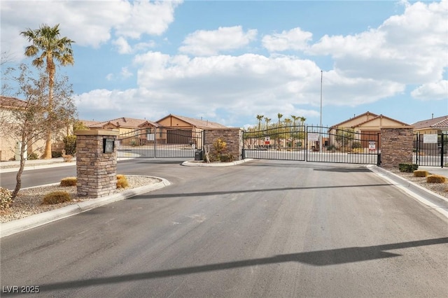 view of street featuring a gate, a gated entry, and curbs