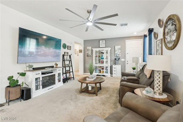 living area with a ceiling fan, visible vents, and light colored carpet