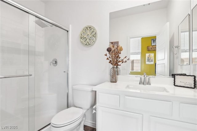 full bathroom featuring a shower with shower door, plenty of natural light, vanity, and toilet