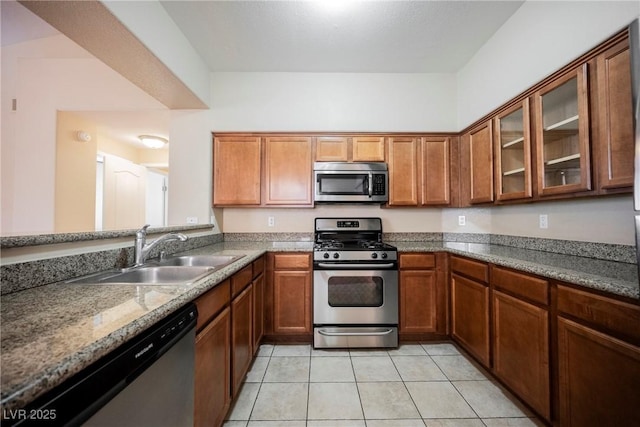 kitchen featuring stainless steel appliances, light tile patterned flooring, sink, and stone counters