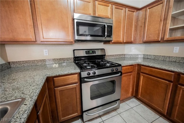 kitchen featuring light stone counters, sink, light tile patterned floors, and appliances with stainless steel finishes