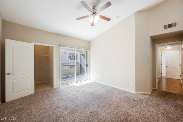 unfurnished bedroom with a spacious closet, high vaulted ceiling, a closet, and carpet