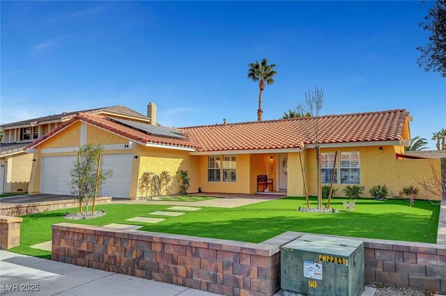 view of front facade with a garage, a front yard, and solar panels