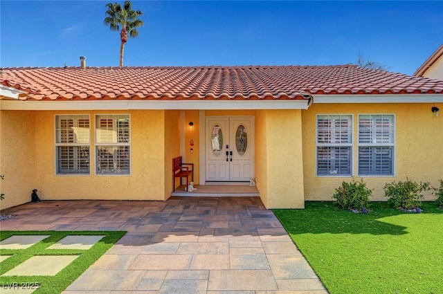 view of exterior entry with a yard and a patio